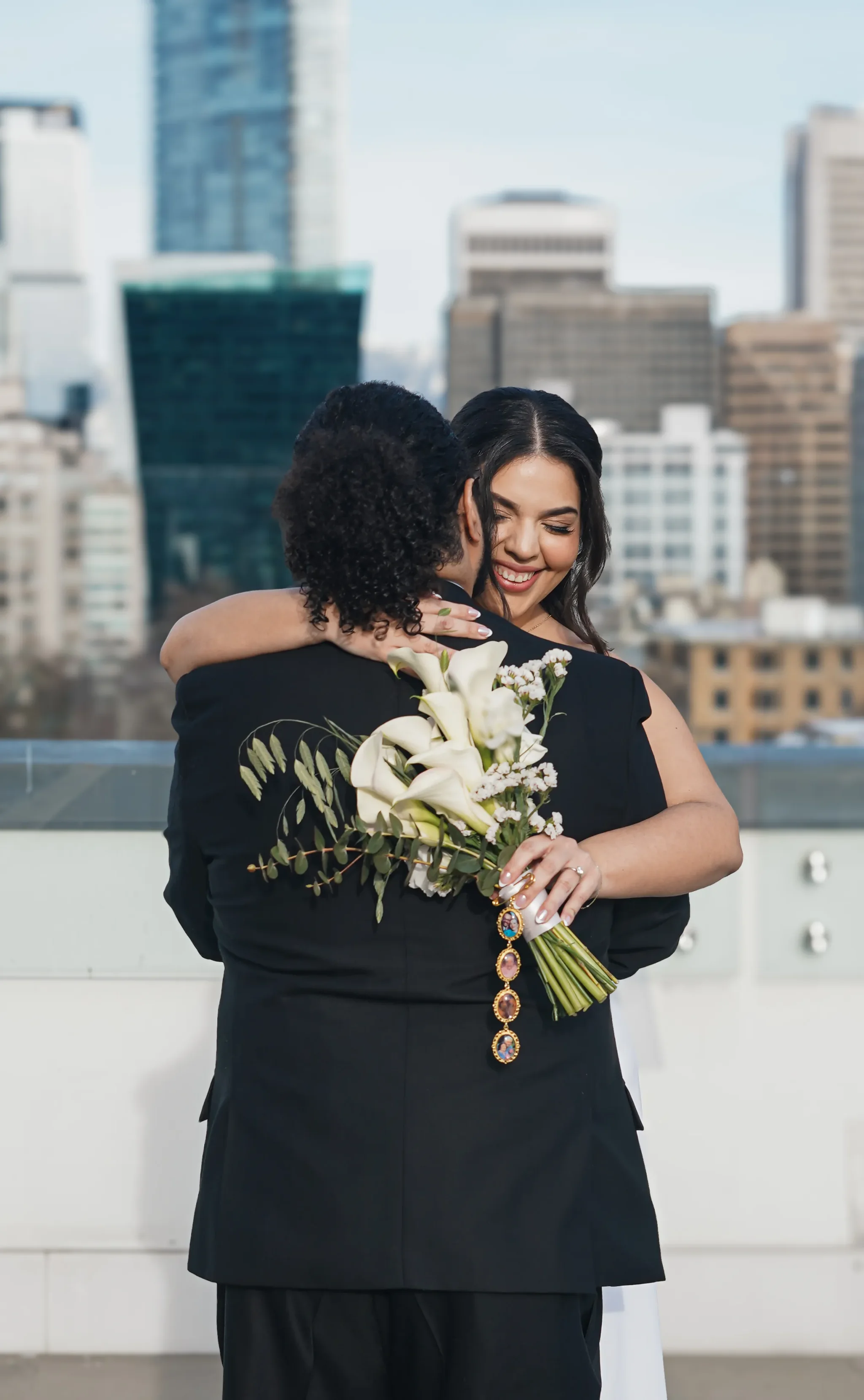 A couple embracing with the Vancouver skyline behind them